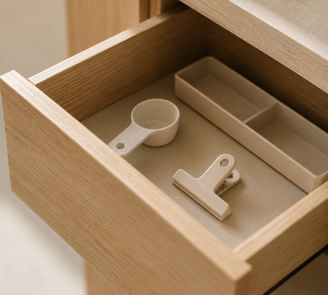 Open light oak drawer with neatly arranged everyday homeware accessories